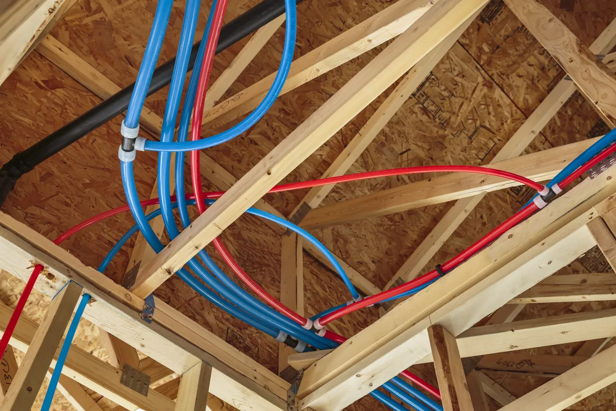 Red and blue PEX water lines run through attic trusses – Before Your Rinnai Tankless Water Heater Installation for Coto de Caza, CA homes